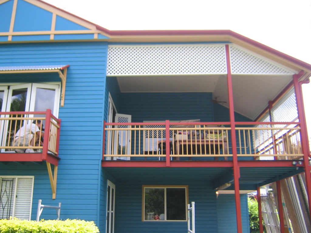 Blue weatherboard Queenslander with red and cream painted trim and balustrades